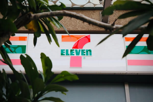 Branches of a tree with a 7 Eleven store sign in the background