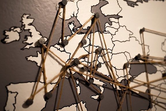 An image of a sepia toned map of Europe, with pins pushed into several countries and a string woven between the pins