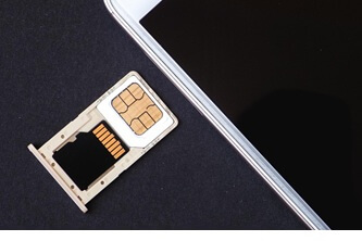 An image of a mobile phone with its SIM card tray outside that contains a loaded SIM card on it