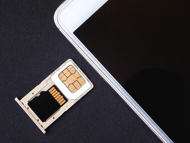 An image of a mobile phone with its SIM card tray outside that contains a loaded SIM card on it