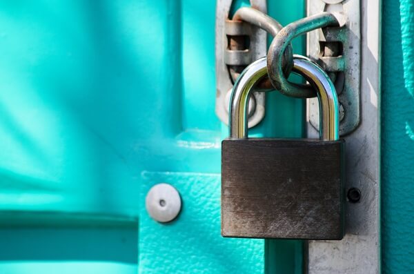 A zoomed in image of a lock on a chain tying two metal doors