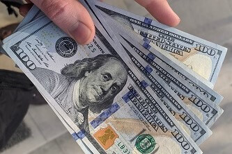 A person holding a fan of 100 US Dollar banknotes