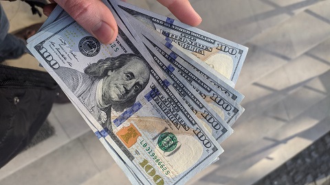 A person holding a fan of 100 US Dollar banknotes