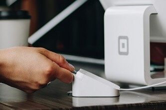 A person making a payment with a card and card reader at a kiosk in a store