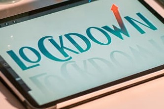 A silver iPhone 6 beside an iPad and a MacBook with the word lockdown displayed on the iPad
