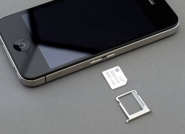 An image of an iPhone with its SIM card and SIM tray pulled out