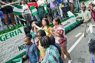Nigerians marching on a street with Nigerian flags in hand