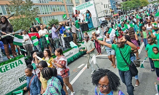 Nigerians marching on a street with Nigerian flags in hand