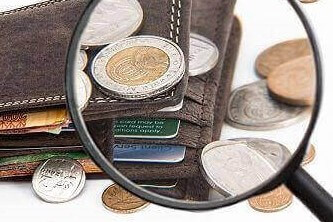 A wallet with coins, currency notes and cards viewed through a magnifying lens