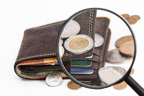 A wallet with coins, currency notes and cards viewed through a magnifying lens