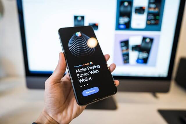 An image of a person holding a phone with a digital wallet application on it