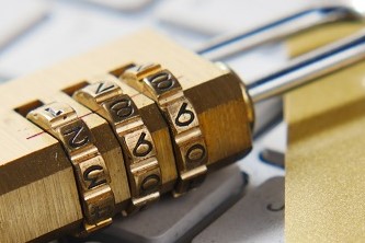 A padlock and couple of credit cards placed on a computer keyboard
