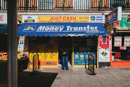 A person standing in front of a store that also provides money transfer services