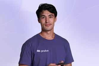 An image of a smiling young man with a Profee t-shirt on and a mobile phone in hand