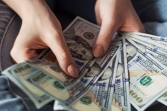 A person holding a fan of 100 US Dollar banknotes