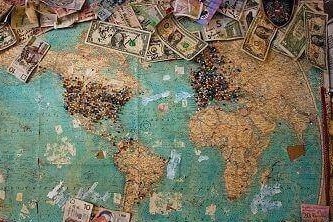A world map is filled with types of money and pushpins