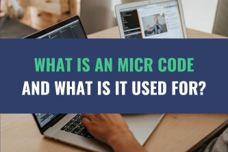 An image of a person using a laptop placed on a desk with the title - What Is An MICR Code And What Is It Used For?