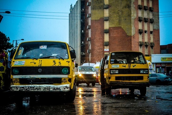 Yellow colored vans on a road with an old apartment building in the background